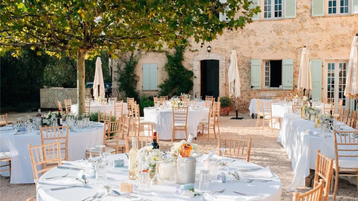 Tables set up for a wedding in the South of France with charming stone property in the backdrop