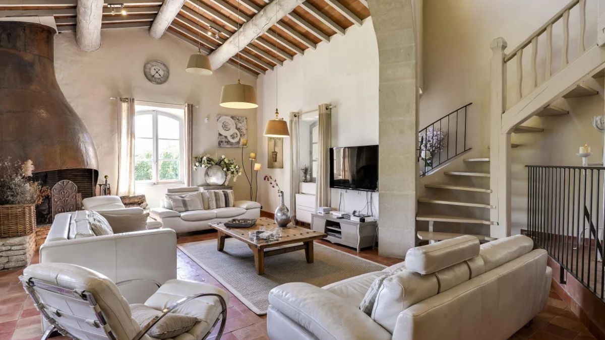 Interior of charming Provencal mas with beamed cealing and large copper fireplace
